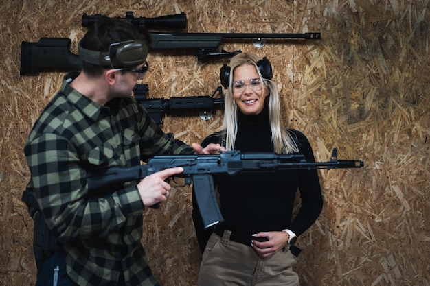 Photo a shooting instructor teaches a girl to shoot from an ak 74m rifle at a shooting range