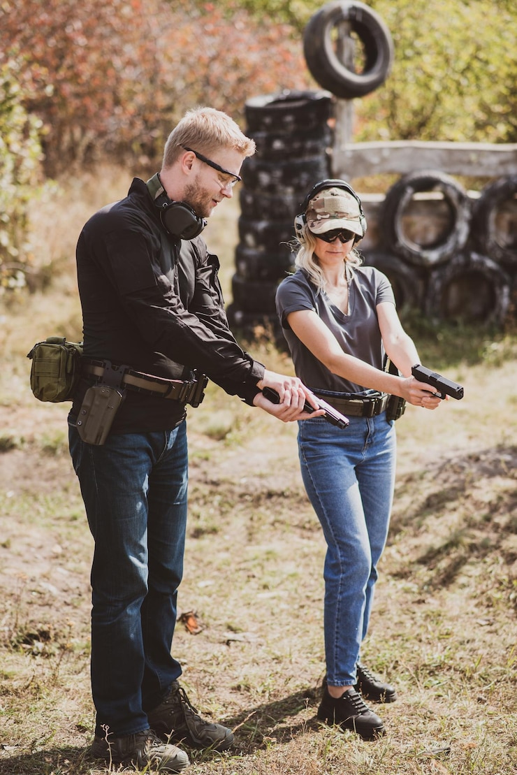 Photo shooting instructor teaching a woman how to properly handle a weapon at the shooting range