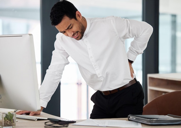 Shooting pains are never fun Shot of a young businessman experiencing back pain at work