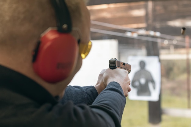 Foto sparo con una pistola uomo che mira la pistola nel poligono di tiro