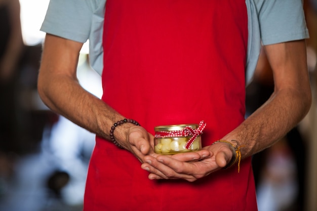 Photo shop assistant holding a jar of pickle in grocery shop