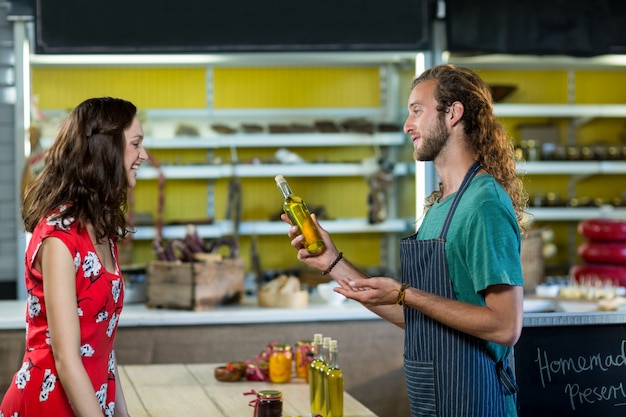 Shop assistant offering olive oil bottle to the customer