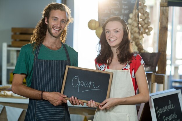 Shop assistants holding open sign board