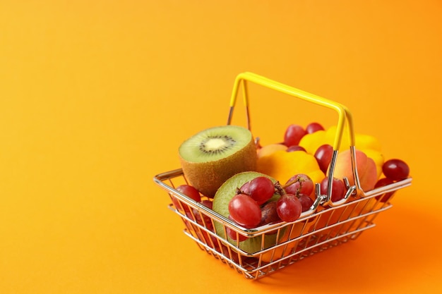 Shop basket with vegetables and fruits on orange background