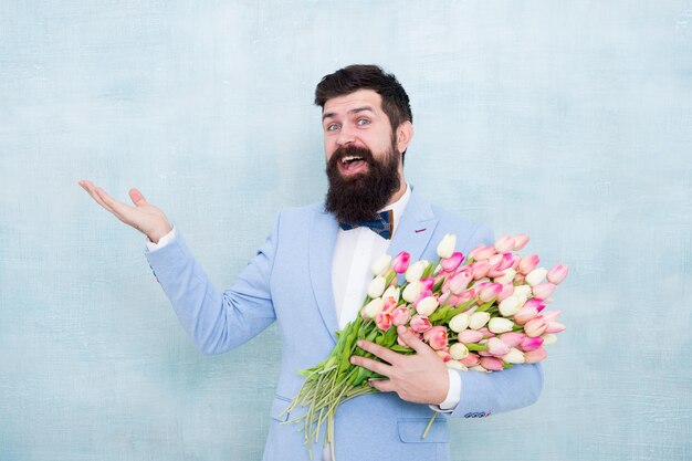 今すぐ購入チューリップと幸せなヒップスター春の花を持つひげを生やした男開花プレゼントバレンタインデーのための花のプレゼントバレンタインまたは女性の日のプレゼントバレンタインの男は空の手のコピースペースを保持します