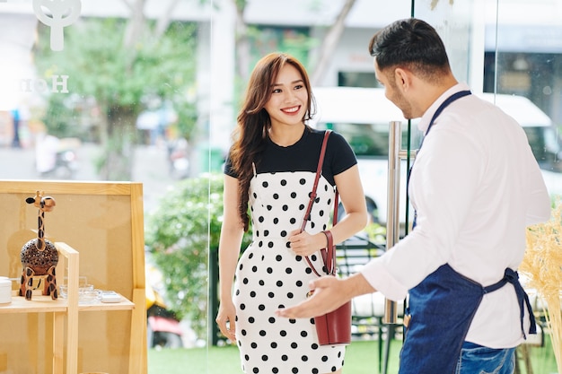 Shop owner holding door for customer