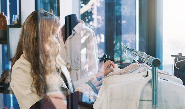 Foto shop till you drop shot van een jonge vrouw die door kleding snuffelt in een boetiek