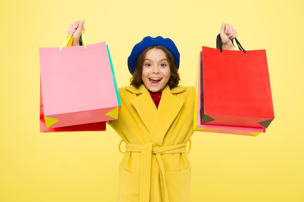 Shop with discount card Get discount shopping on birthday or holiday Fashionista adore shopping Obsessed with shopping Girl cute kid hold shopping bags on yellow background Mid season sale