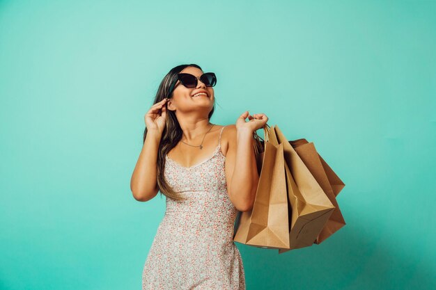 Shopaholic fashion woman latinx with sunglasses looking away holding shopping bags