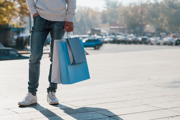 Shopaholic levensstijl. bijgesneden schot van man in casual outfit reputatie met pakketten.