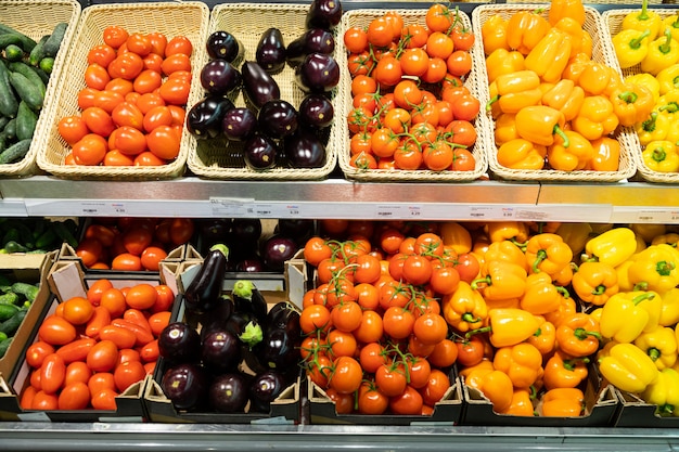 Shopboard counter with wicker baskets and lug boxes with tomatoes, squash, orange and yellow pepper and eggplant