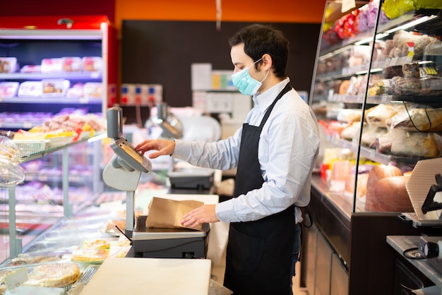 Shopkeeper running business while wearing mask, coronavirus pandemic concept