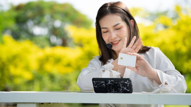 Shopper glimlach meisje online kopen of online werken met een slimme telefoon en creditcard zittend op een bankje in een stadspark in de zomer Smile meisje blij met haar kaart portret van een jonge executive