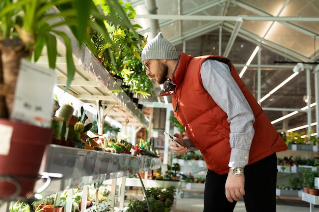 園芸用品センターの棚にある鉢植えの生きた植物を見ている買い物客