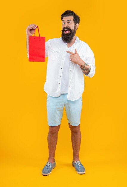 Shopper man at shopping isolated on yellow point finger shopper man at shopping in studio