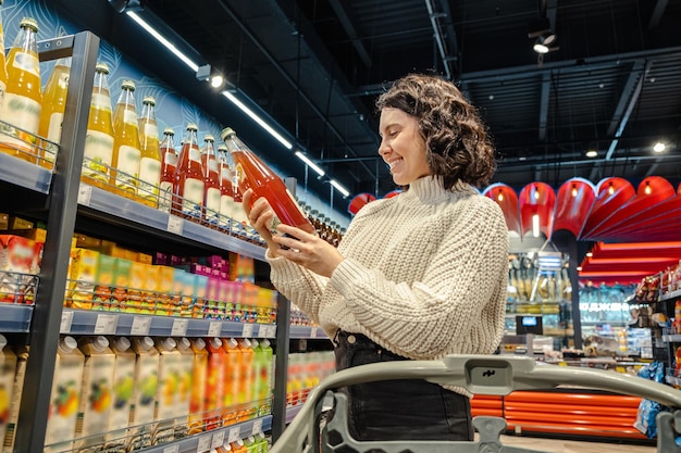 Shopper selects juice in grocery store with cart