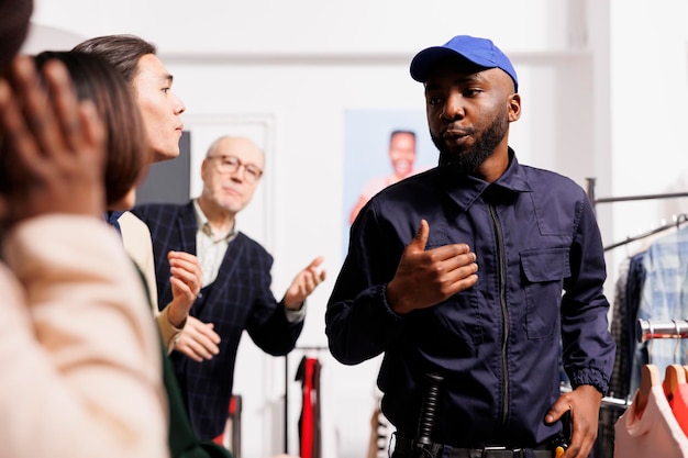 Photo shoppers yell at african american man security officer, waiting in line at fashion store entrance. diverse people customers being rude and unpleasant with shopping mall employee during black friday