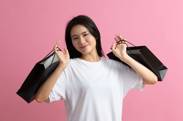 Shopping asian happy woman holding shopping bags on pink background