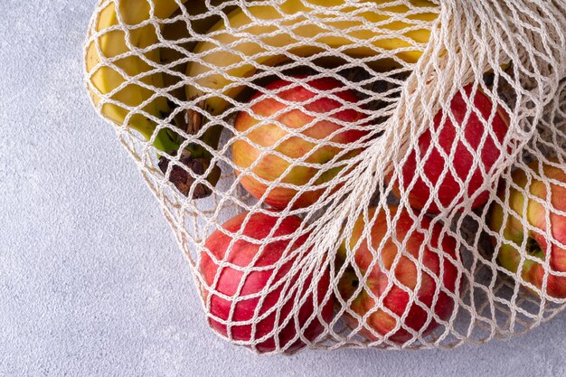 Shopping bag made of environmentally friendly material with bananas and apples on a gray background