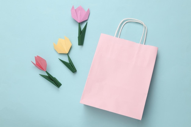 Shopping bag and origami tulips on a blue background Spring sale Top view