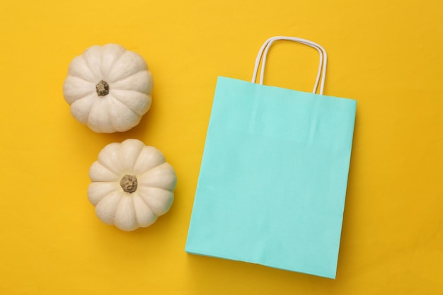 Shopping bag and pumpkins on a yellow background halloween\
shopping top view