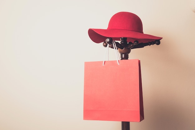 Foto shopping bag e cappello rosso appeso su gancio di legno