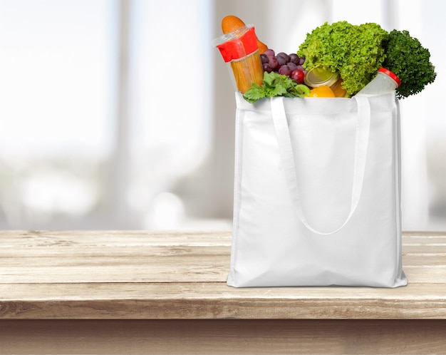 Photo shopping bag with grocery products on blurred background