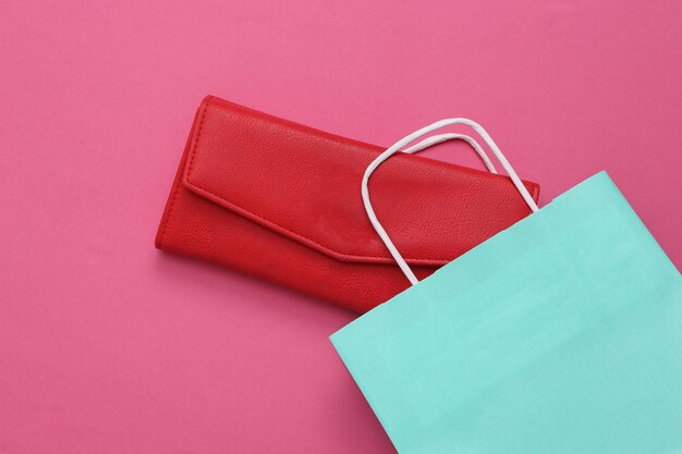 Shopping bag with red wallet on pink background Shopping concept Top view