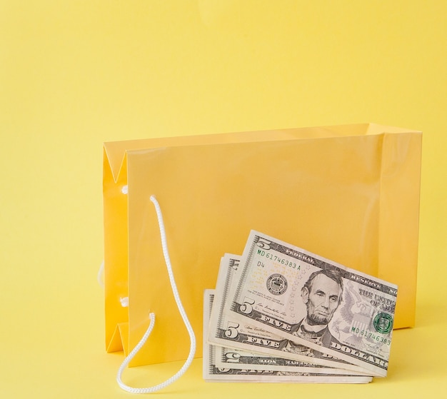 Shopping bags and dollars on a yellow background.