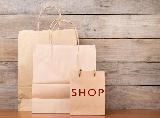 Shopping bags with inscription SHOP on wooden background