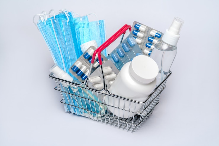 Shopping basket cart full of pills and medical supplies over light grey background
