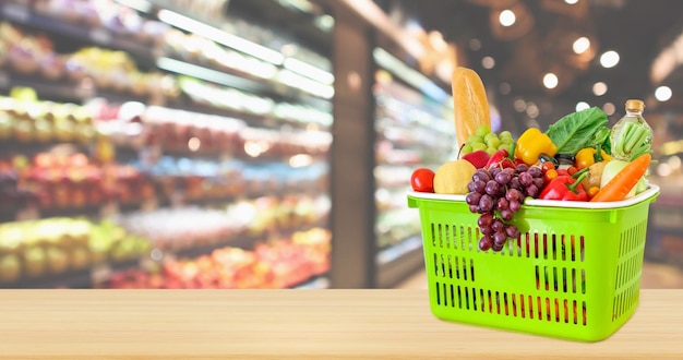 Shopping basket filled with fruits and vegetables on wood table\
with supermarket grocery store blurred defocused background with\
bokeh light