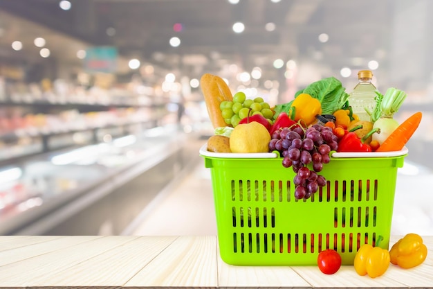 나무 테이블에 과일과 야채로 가득 찬 쇼핑 바구니와 슈퍼마켓 식료품점은 보케 빛으로 흐릿한 배경을 흐리게 합니다.