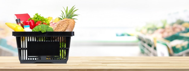 Shopping basket full of food and groceries on the table in supermarket 