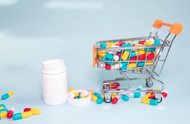 Shopping basket and pills on blue background. The concept of buying drugs online.