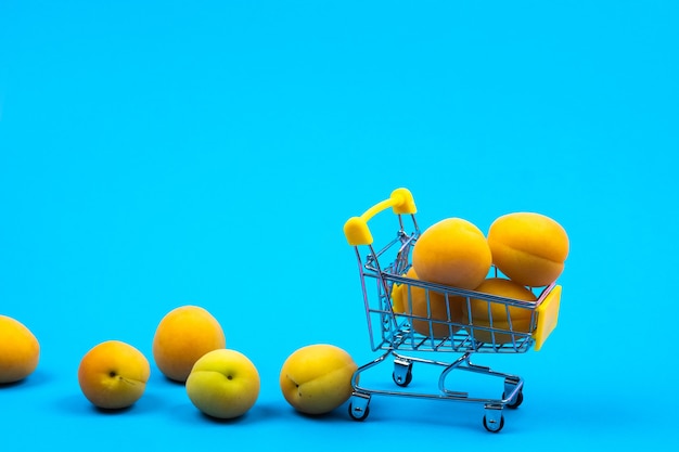 Shopping basket with apricots on a blue background