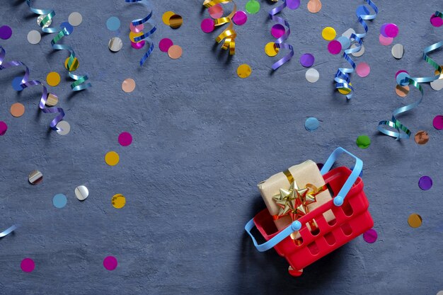 Carrello con confezione regalo e festosa tinsel piatto su sfondo scuro vista dall'alto