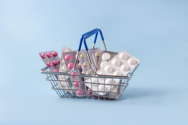 Shopping basket with pills on a blue background.