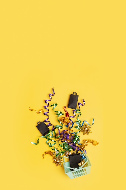 Shopping basket with spirals of tinsel and bag on top on a colored background Copy space