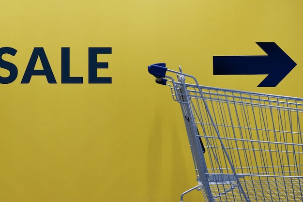 Shopping cart against text and arrow symbol on wall