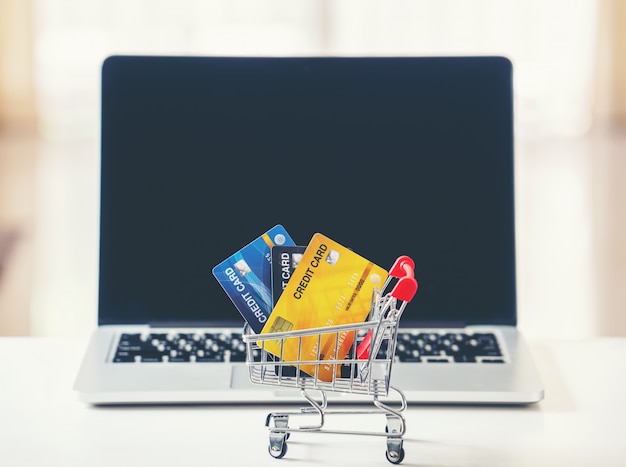 Shopping cart and credit card with laptop on the desk