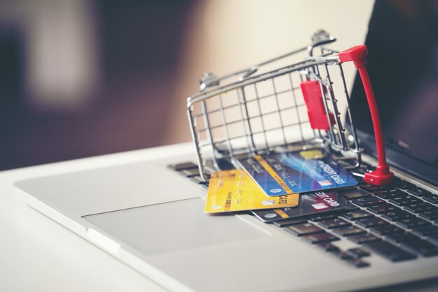 Shopping cart and credit card with laptop on the desk