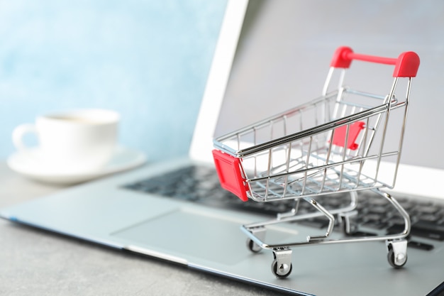 Shopping cart, cup of coffee and laptop copy space