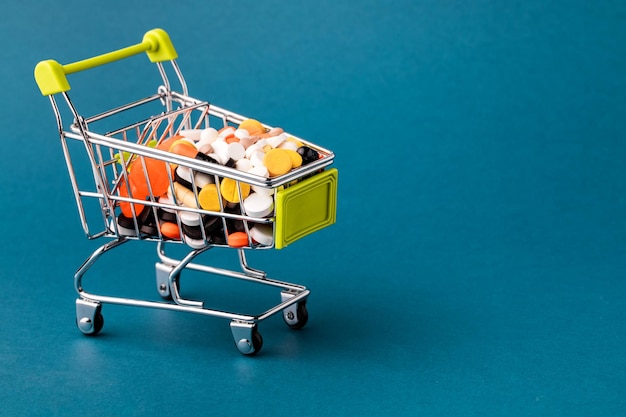 Shopping cart filled with pills Blue background Concept full set of medicines in the store Copy space for text