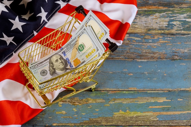 Photo shopping cart financial concept with us dollars banknotes on american flag
