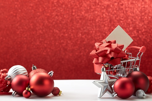  Shopping cart full of Christmas ornaments on red background