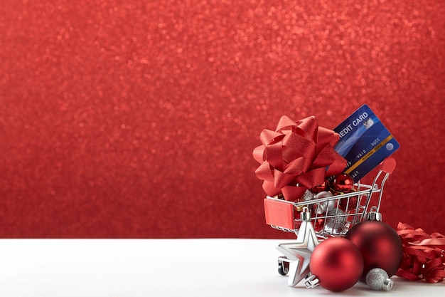  Shopping cart full of Christmas ornaments on red background