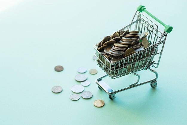 Shopping cart full of coins over the green background