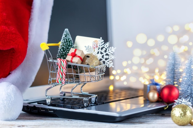 Carrello pieno di scatole regalo e albero di natale sulla tastiera del computer portatile concetto di shopping online e vendita di vacanze