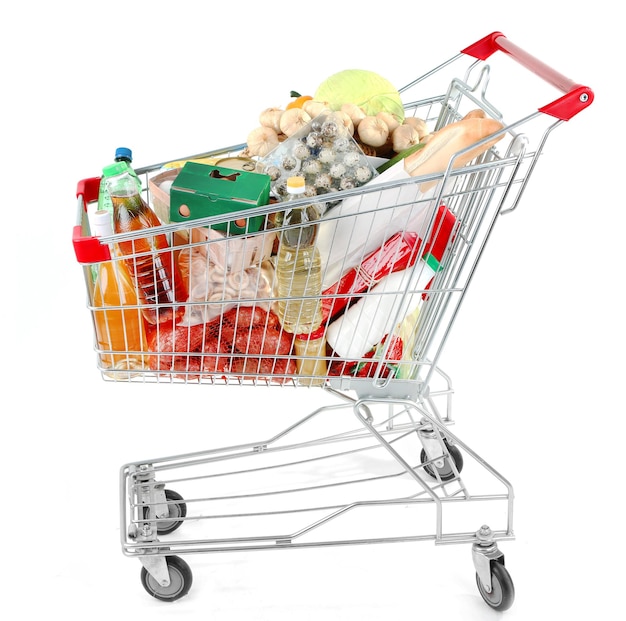 Shopping cart full with various groceries isolated on white